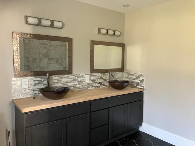bathroom featuring tile patterned floors, a sink, backsplash, and baseboards