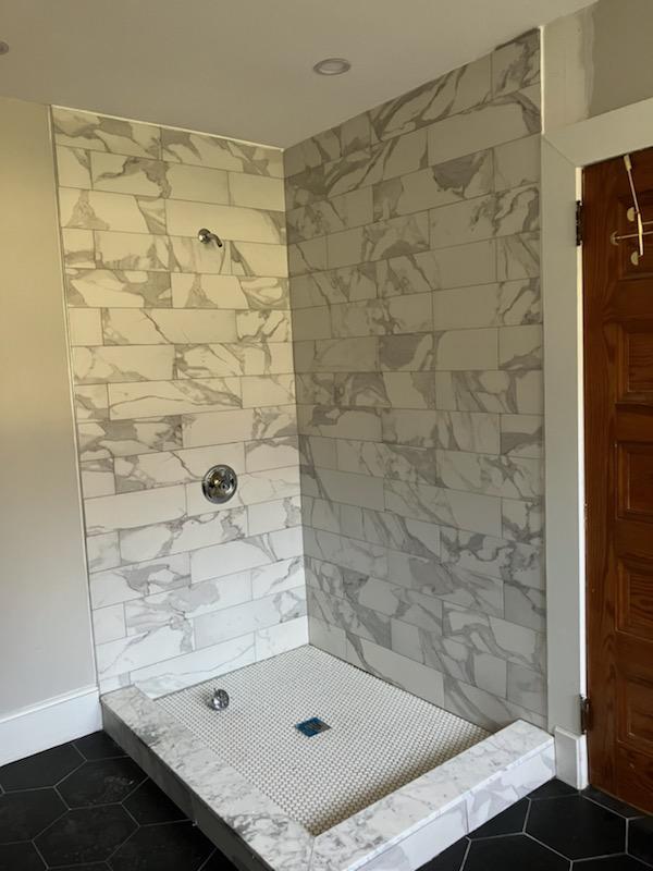 bathroom with tiled shower and tile patterned flooring