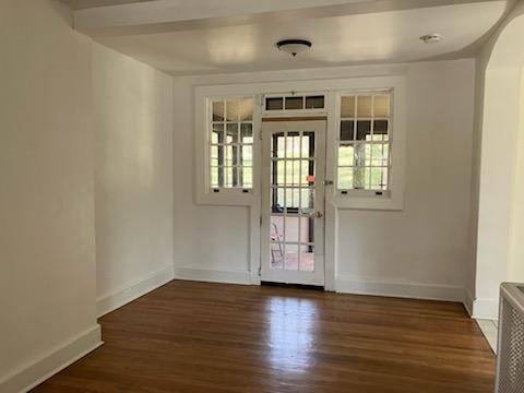 doorway featuring baseboards, arched walkways, and wood finished floors