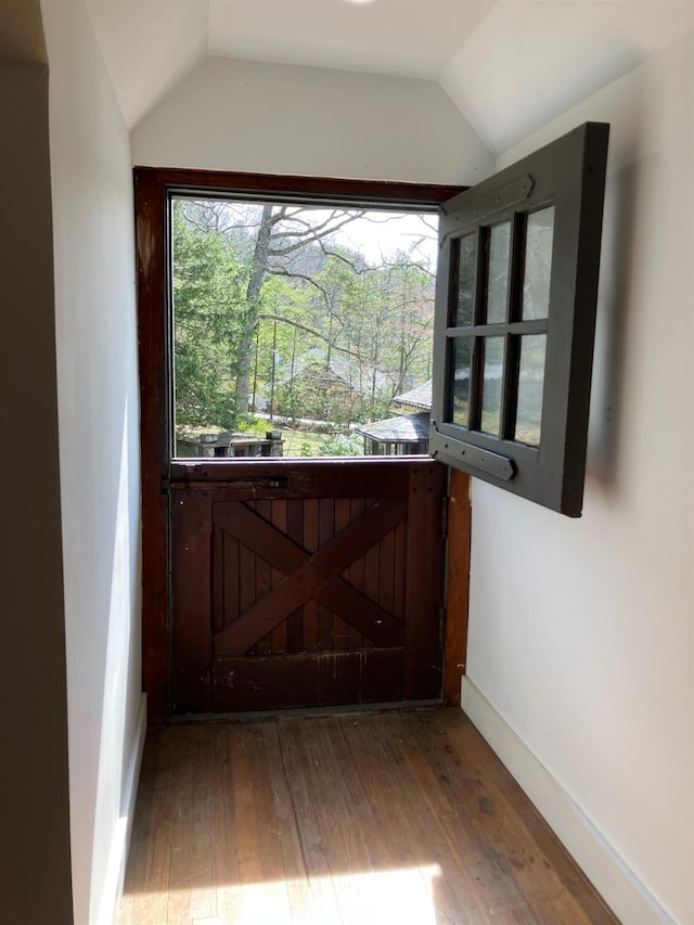 doorway featuring baseboards, vaulted ceiling, and hardwood / wood-style flooring
