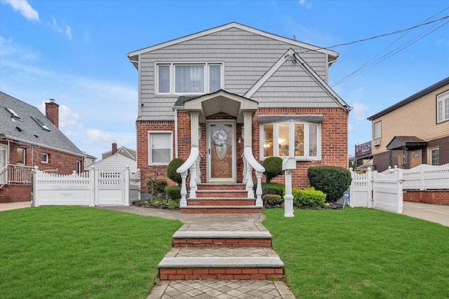 view of front facade featuring brick siding, a front lawn, fence, and a gate