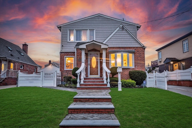 view of front of house featuring brick siding, fence, a front lawn, and a gate
