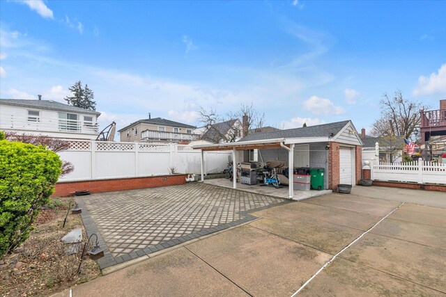 view of patio / terrace with a garage, a fenced backyard, and an outdoor structure