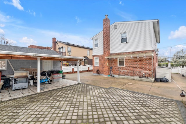 rear view of house with a patio area, fence, and brick siding