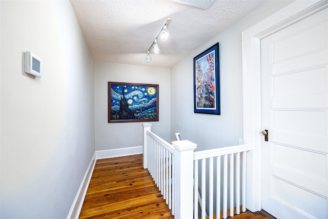 3 Druid Hill Rd, Port Jefferson, NY 11777 - hallway with an upstairs landing, wood finished floors, baseboards, a textured ceiling, and track lighting