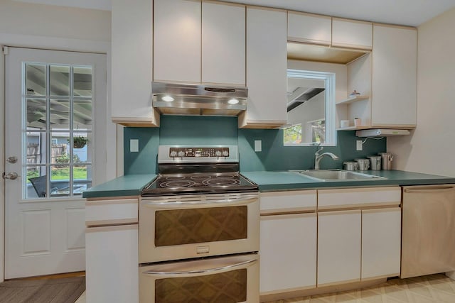 kitchen with a sink, appliances with stainless steel finishes, extractor fan, and white cabinetry