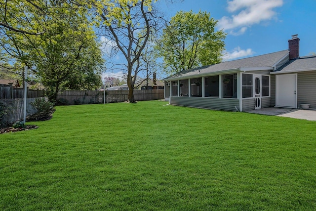 view of yard with a patio, a fenced backyard, and a sunroom