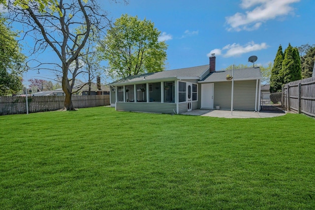 rear view of house with a sunroom, a fenced backyard, a chimney, a patio area, and a lawn