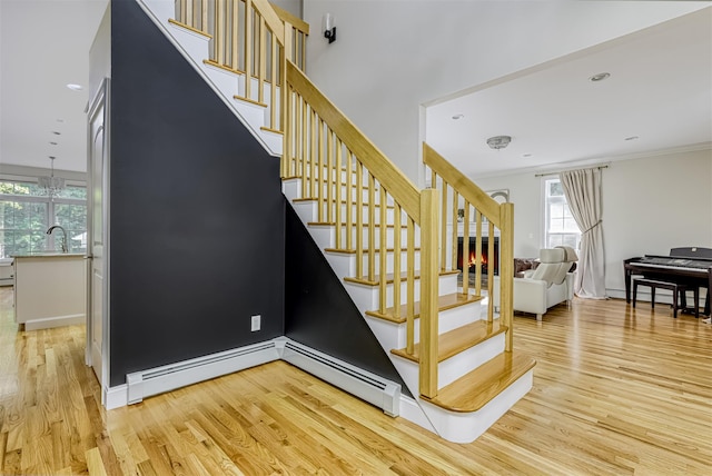 stairs with baseboards, wood finished floors, ornamental molding, and a healthy amount of sunlight