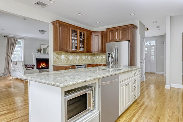 kitchen with a sink, visible vents, light stone counters, and stainless steel appliances