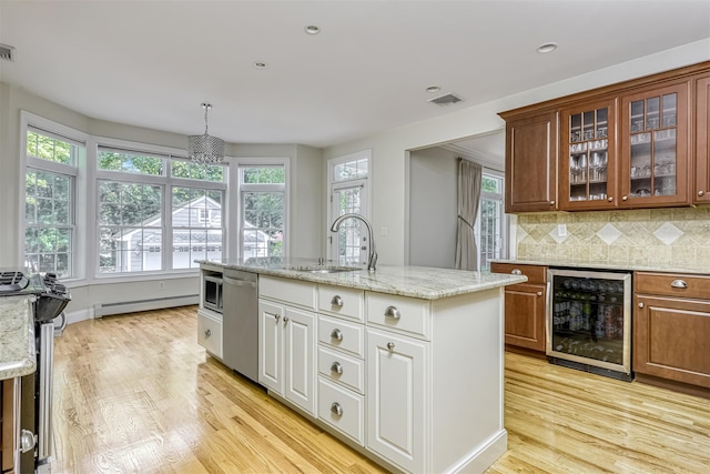 kitchen with a baseboard radiator, appliances with stainless steel finishes, beverage cooler, and plenty of natural light