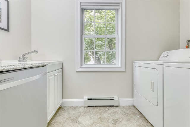 washroom featuring washer and dryer, baseboard heating, baseboards, and cabinet space