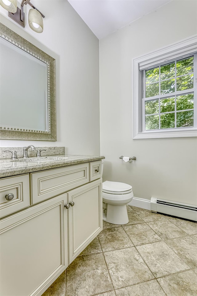half bath with toilet, a baseboard radiator, vanity, and baseboards