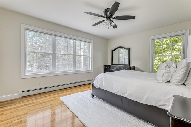 bedroom featuring ceiling fan, a baseboard radiator, and wood finished floors