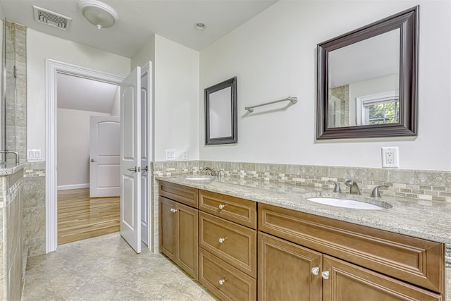 bathroom with a sink, visible vents, double vanity, and tiled shower