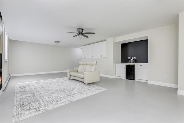 unfurnished room featuring concrete floors, a baseboard heating unit, baseboards, and wine cooler