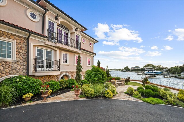 1101 Harbor Rd, Hewlett, NY 11557 - exterior space with a water view, a tiled roof, stone siding, a dock, and a balcony