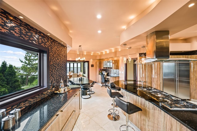 1101 Harbor Rd, Hewlett, NY 11557 - kitchen featuring light brown cabinets, a breakfast bar, dark stone countertops, a chandelier, and hanging light fixtures