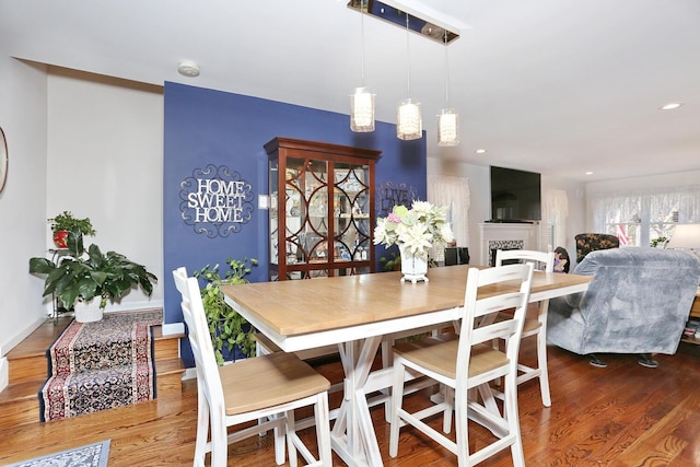 dining room featuring recessed lighting, wood finished floors, and a fireplace