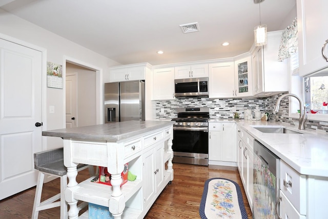 kitchen featuring stainless steel appliances, white cabinets, a sink, and backsplash