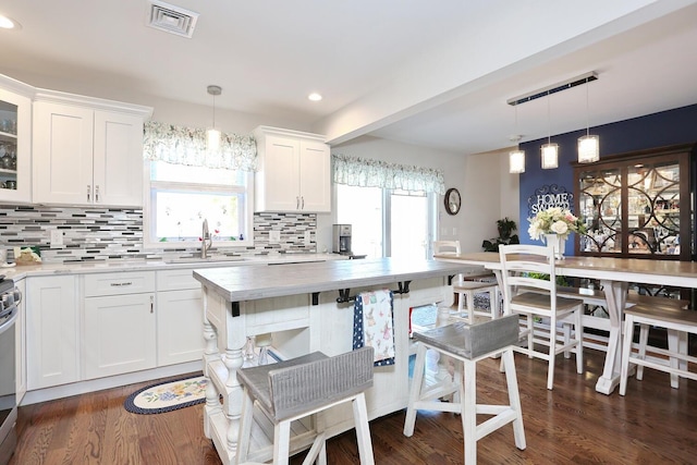 kitchen featuring a sink, visible vents, decorative backsplash, and white cabinetry