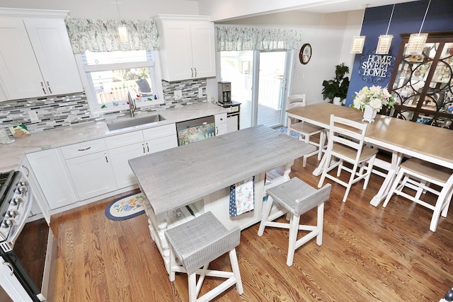 kitchen with tasteful backsplash, range, white cabinets, stainless steel dishwasher, and a sink