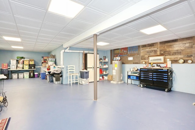finished below grade area with water heater, freestanding refrigerator, and wooden walls
