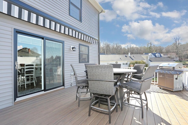 wooden deck with outdoor dining space and area for grilling