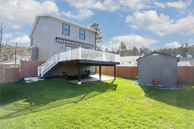 rear view of property featuring a shed, a yard, a fenced backyard, and an outbuilding