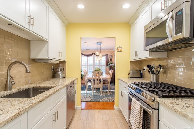 60 Erin Ln Unit 60, East Setauket, NY 11733 - kitchen with stainless steel appliances, white cabinets, a chandelier, decorative backsplash, and recessed lighting