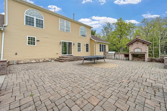rear view of house with a patio, a fireplace, and an outdoor kitchen
