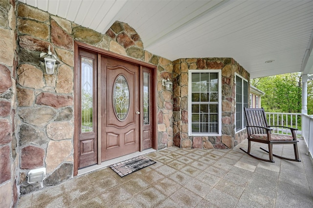 entrance to property featuring stone siding and covered porch