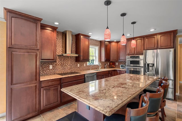 kitchen with a kitchen breakfast bar, wall chimney range hood, light stone countertops, stainless steel appliances, and a sink