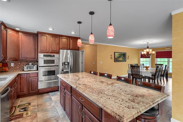 kitchen with light stone countertops, tasteful backsplash, a warming drawer, appliances with stainless steel finishes, and a notable chandelier