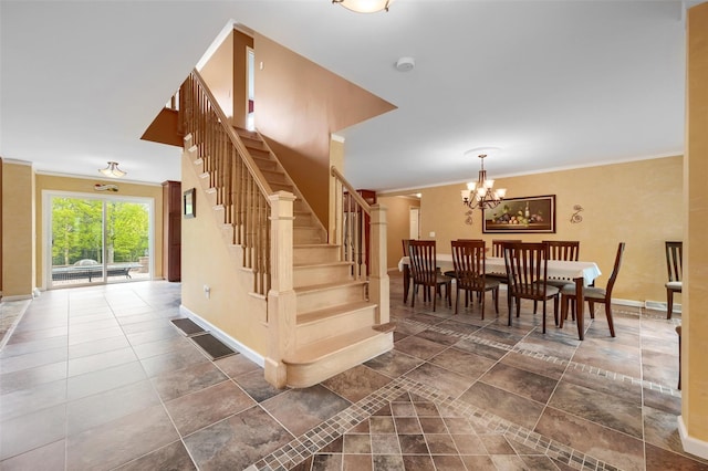 stairway with crown molding, an inviting chandelier, baseboards, and visible vents