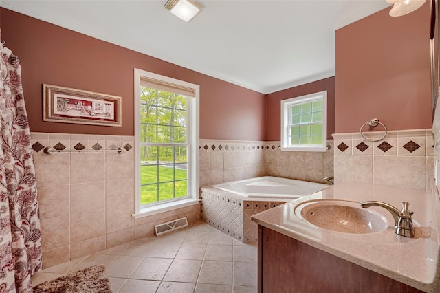 full bathroom featuring tile walls, plenty of natural light, a wainscoted wall, and visible vents