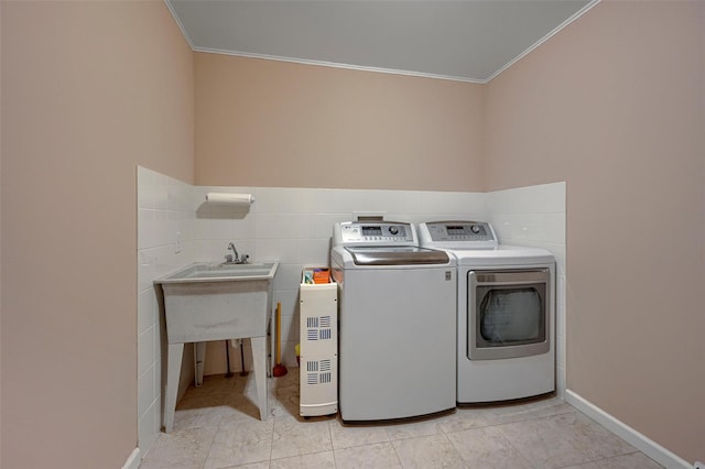 laundry area featuring tile walls, separate washer and dryer, laundry area, and ornamental molding