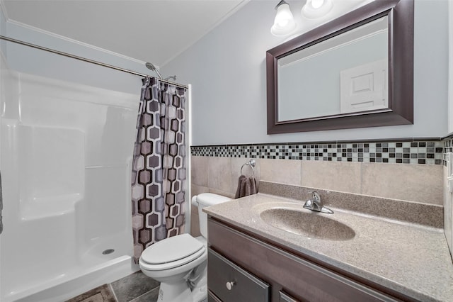 bathroom with a shower stall, a wainscoted wall, toilet, vanity, and tile walls