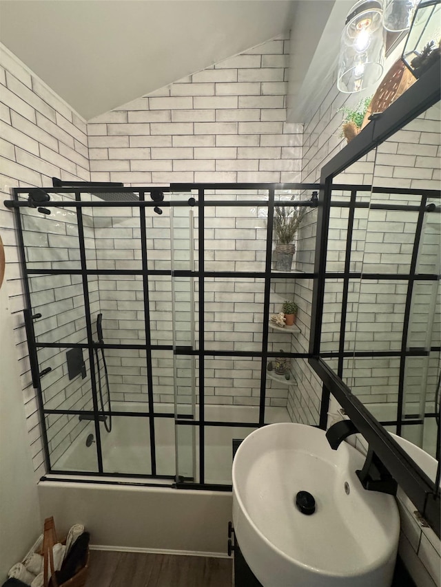 bathroom with lofted ceiling, wood finished floors, and shower / bath combination with glass door