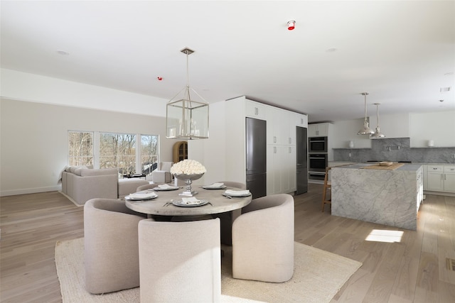 dining room with baseboards, light wood-style floors, a notable chandelier, and visible vents