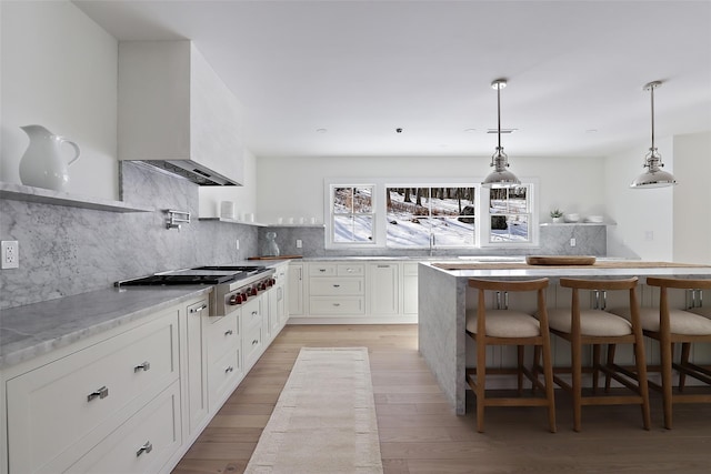 kitchen featuring custom exhaust hood, tasteful backsplash, white cabinetry, and stainless steel gas cooktop