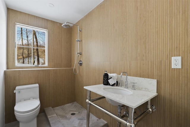 bathroom featuring a tile shower, a sink, and toilet