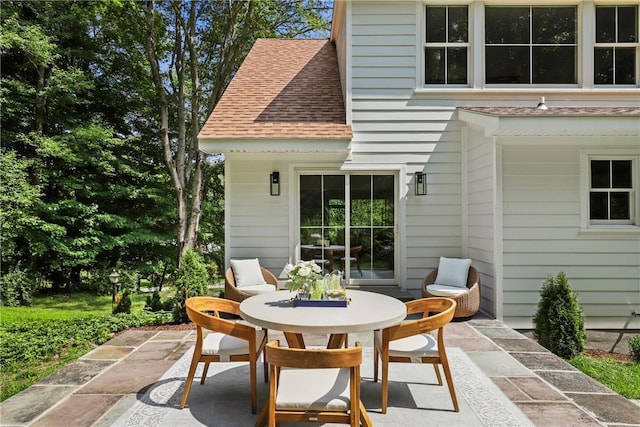 rear view of house with a patio and roof with shingles