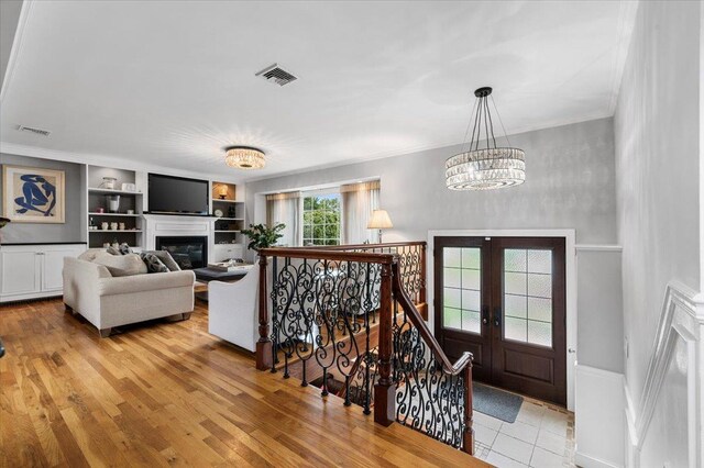 61 Beatrice Ln, Old Bethpage, NY 11804 - foyer featuring a chandelier, french doors, a glass covered fireplace, crown molding, and light wood-style floors