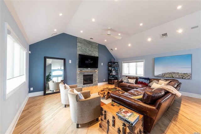 living area featuring a fireplace, vaulted ceiling, ceiling fan, and light wood-style flooring