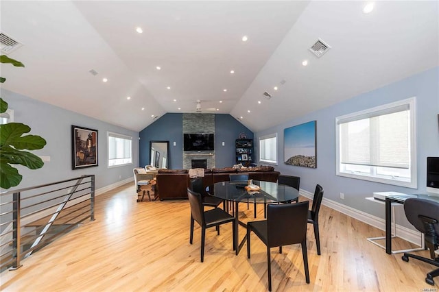 dining room with vaulted ceiling, visible vents, light wood-style floors, baseboards, and a large fireplace
