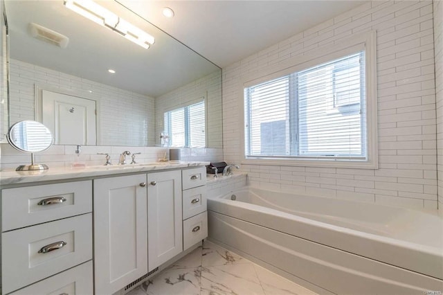 bathroom with a garden tub, marble finish floor, and vanity