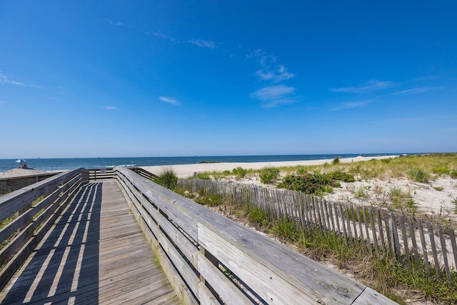view of water feature featuring a view of the beach and fence