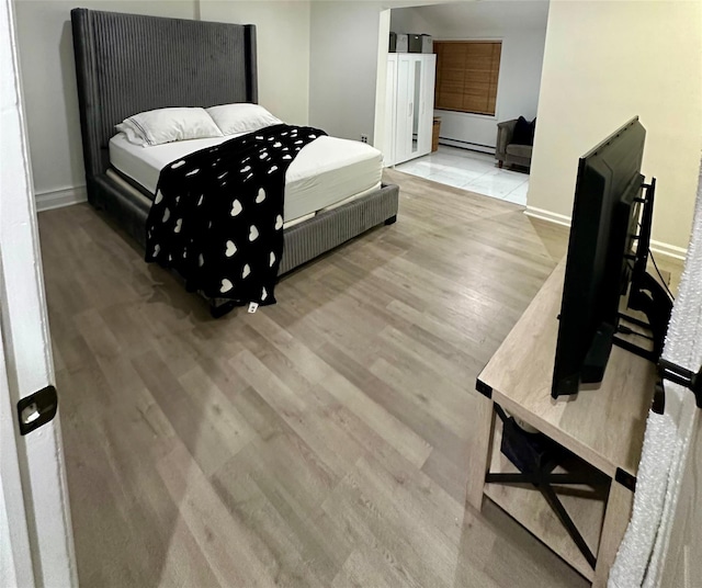 121 W Seaman Ave, Freeport, NY 11520 - bedroom with light wood-style flooring, a baseboard heating unit, and baseboards