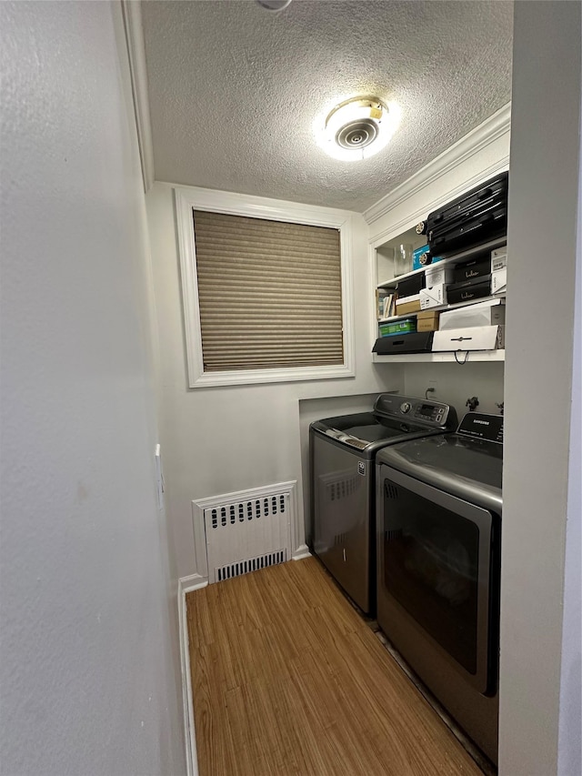 121 W Seaman Ave, Freeport, NY 11520 - clothes washing area featuring laundry area, radiator, a textured ceiling, wood finished floors, and washing machine and dryer
